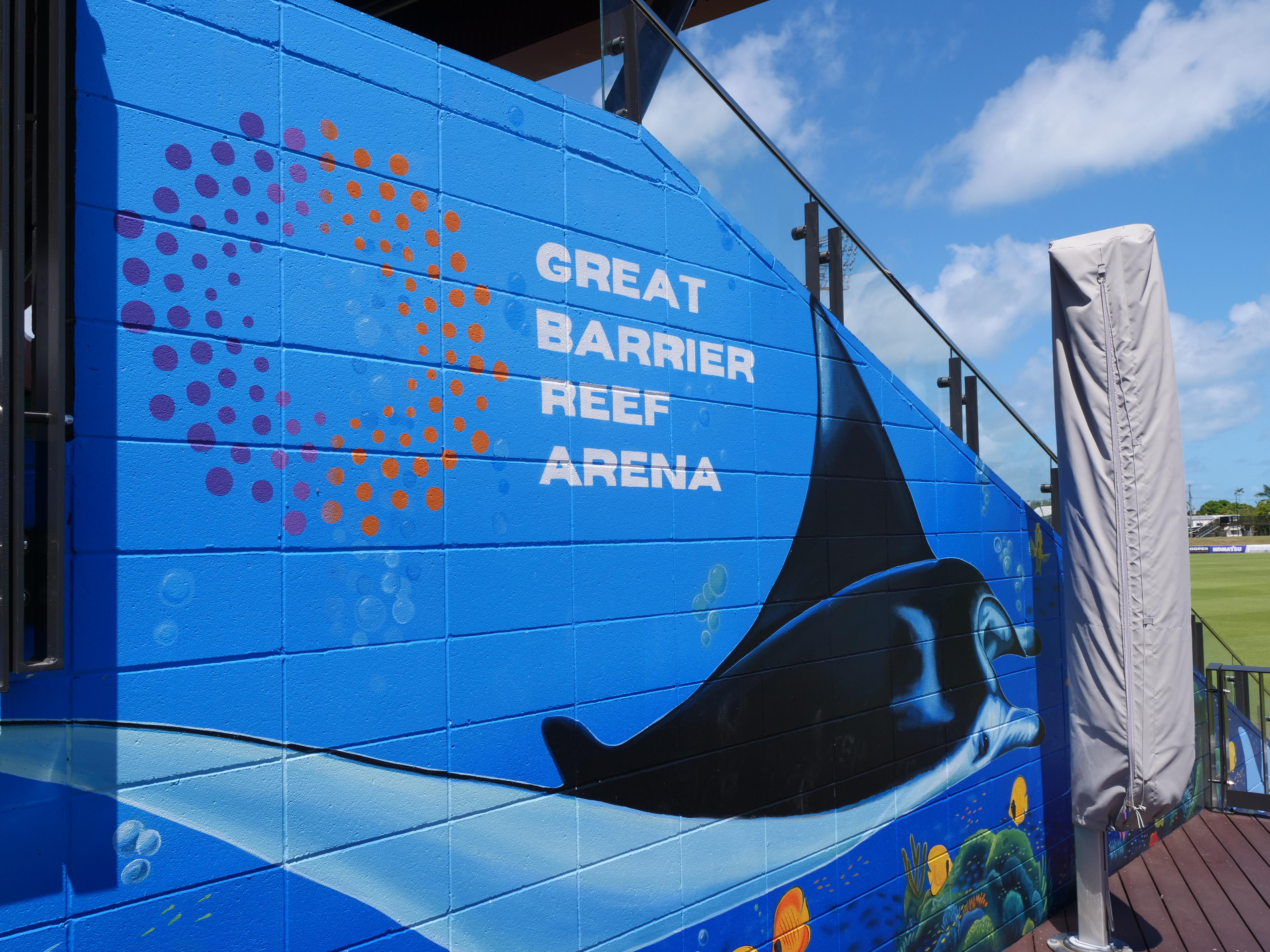 Un mural con el logotipo de Great Barrier Reef Arena y un tiburón al costado de una tribuna. 