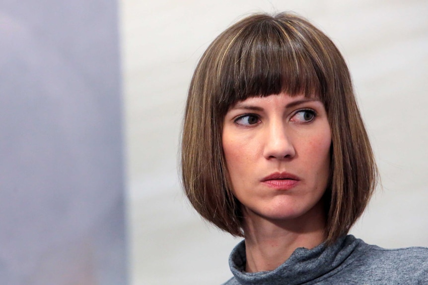 Rachel Crooks stares out the corner of her eye at a press conference