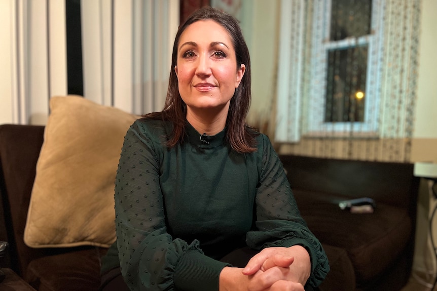 Woman wearing a green blouse sitting on a couch. 