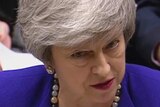 Theresa May, wearing a blue jacket, speaks in the House of Commons