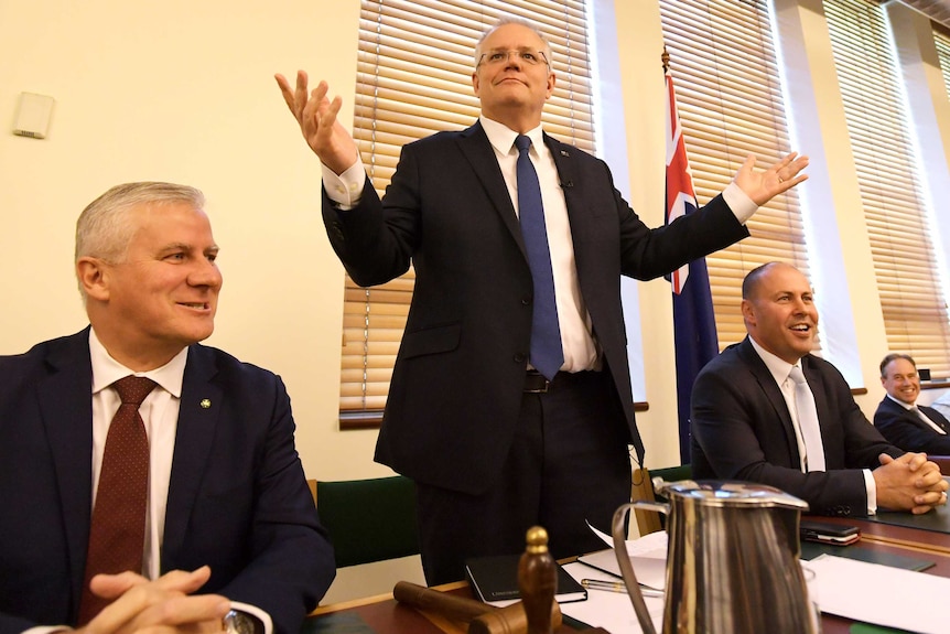 Prime Minister Scott Morrison stands with his arms in the air.