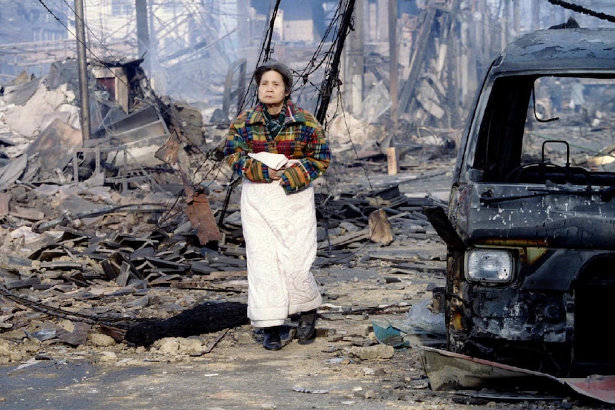 An older woman walks through a destroyed street in Kobe.