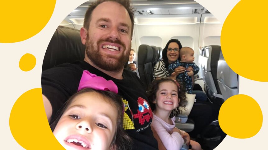 A man taking a selfie with his partner and three kids on a plane.