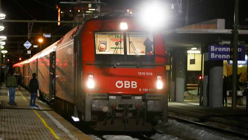 A red train stops at a platform at the Brenner Pass in Italy.