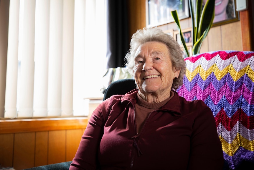  Elderly woman sits in her chair smiling