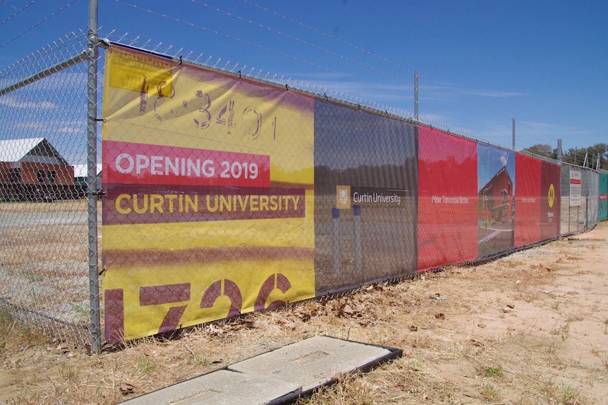 A fence in front of a vacant block with a sign reading 'opening 2019, Curtin University'