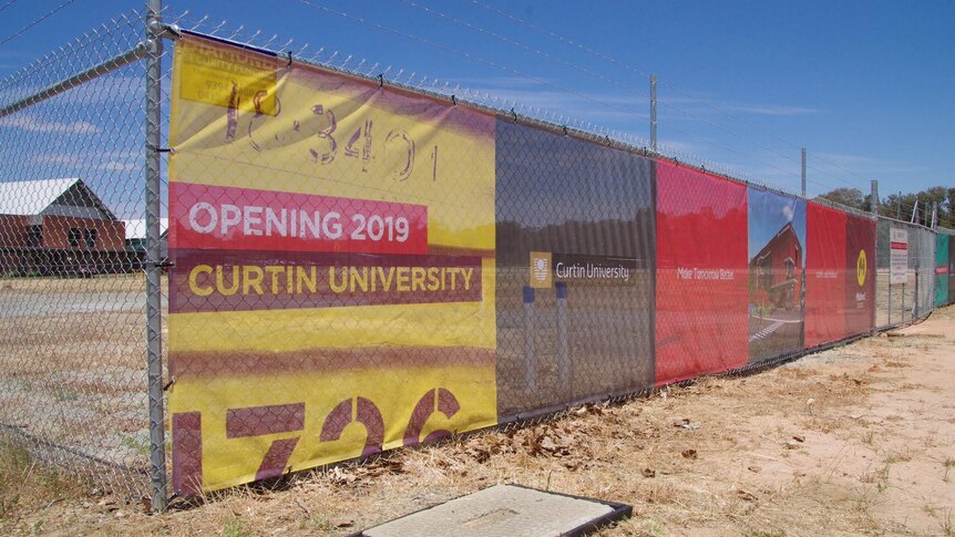 A fence in front of a vacant block with a sign reading 'opening 2019, Curtin University'