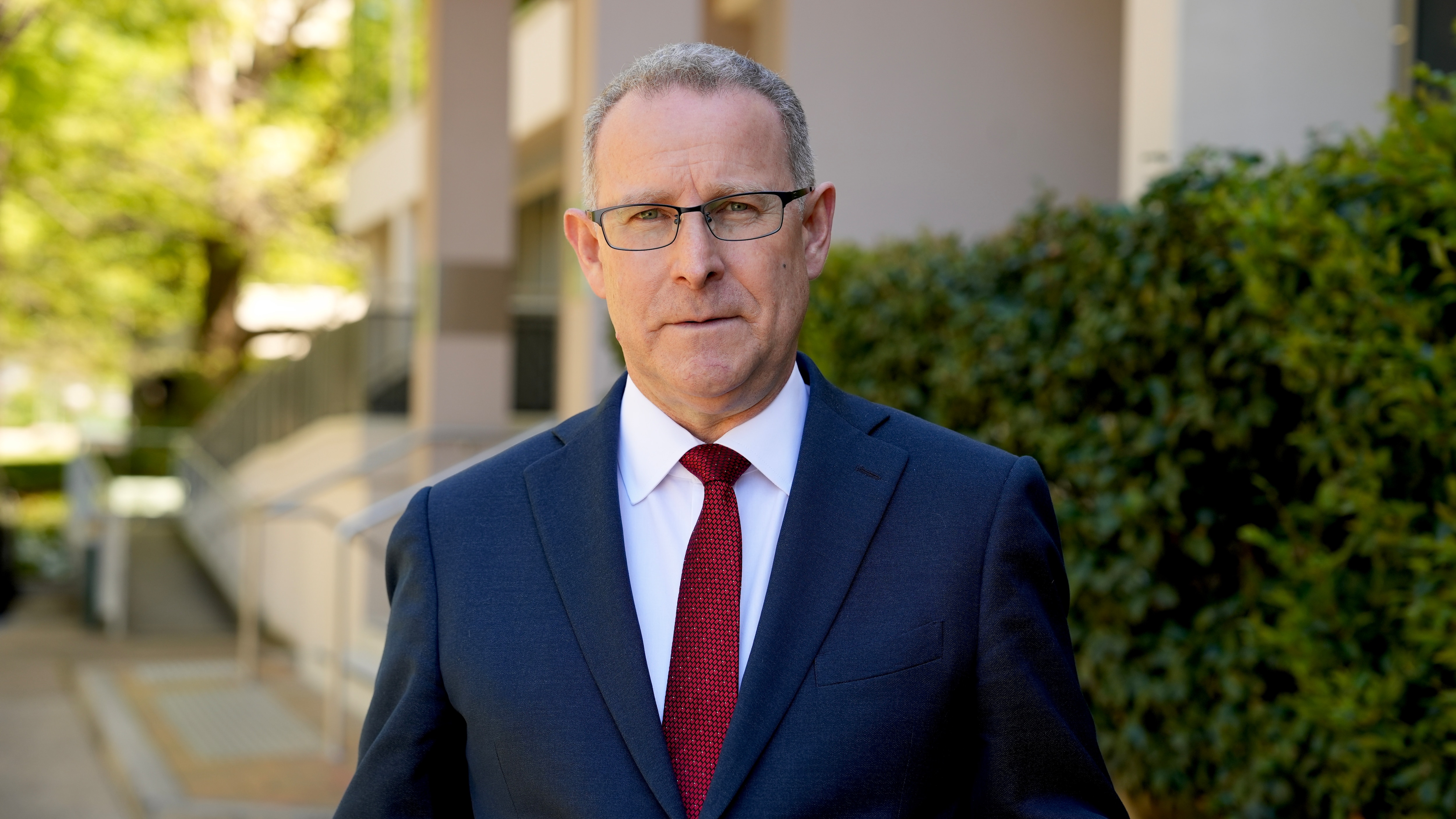 man with grey hair and glasses in a suit