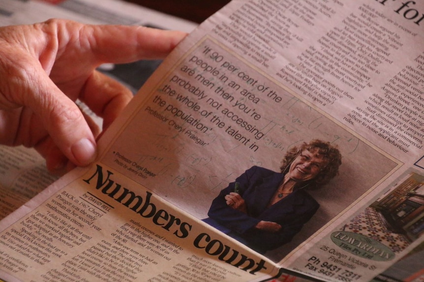 A close-up shot of a woman holding a newspaper article.