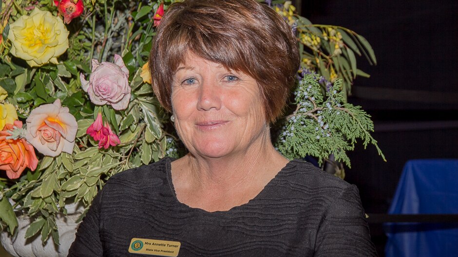 Close up of a woman in front of vase of flowers