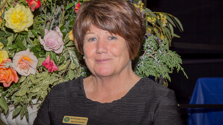 Close up of a woman in front of vase of flowers