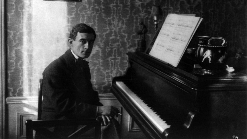 Black and white photograph of composer Ravel sitting at a piano
