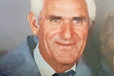 A man with white hair and blue suite poses for the camera.