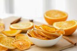 Vivid orange dried orange slices sit in a white bowl.   