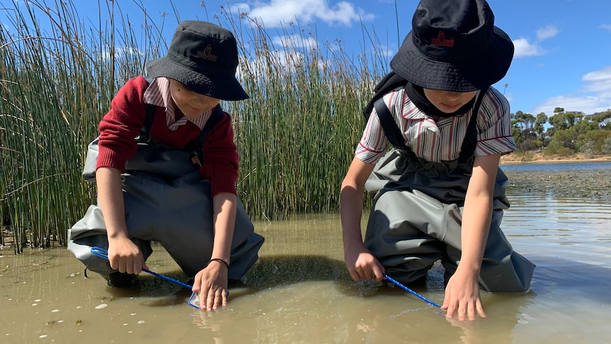 Photo of two children in river water.