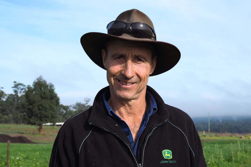 Pemberton potato grower Glen Ryan in black jumper and hat, with fields in the background.