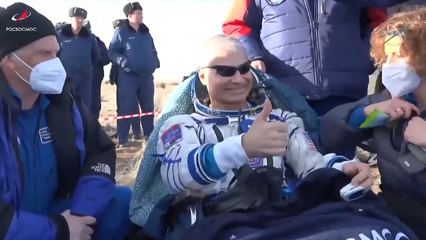 US astronaut gives thumbs up after landing back on earth.
