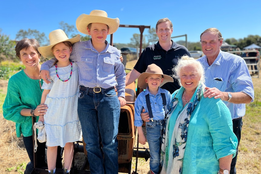 Three children, their mum, grandparents and uncle pose with a tractor.