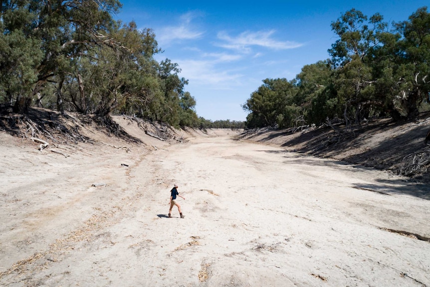 A woman walks across a large dry lake