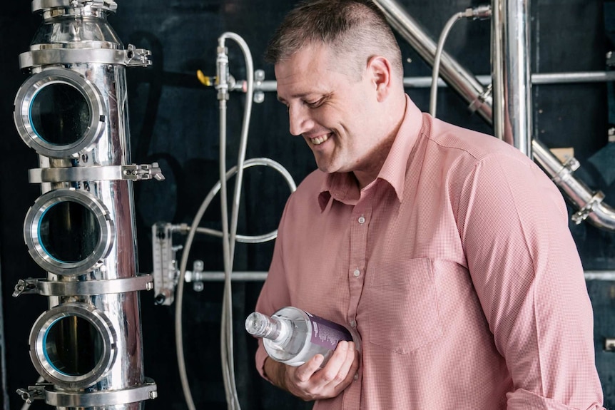 Toby Angstmann with a spiorit bottle in front of a still