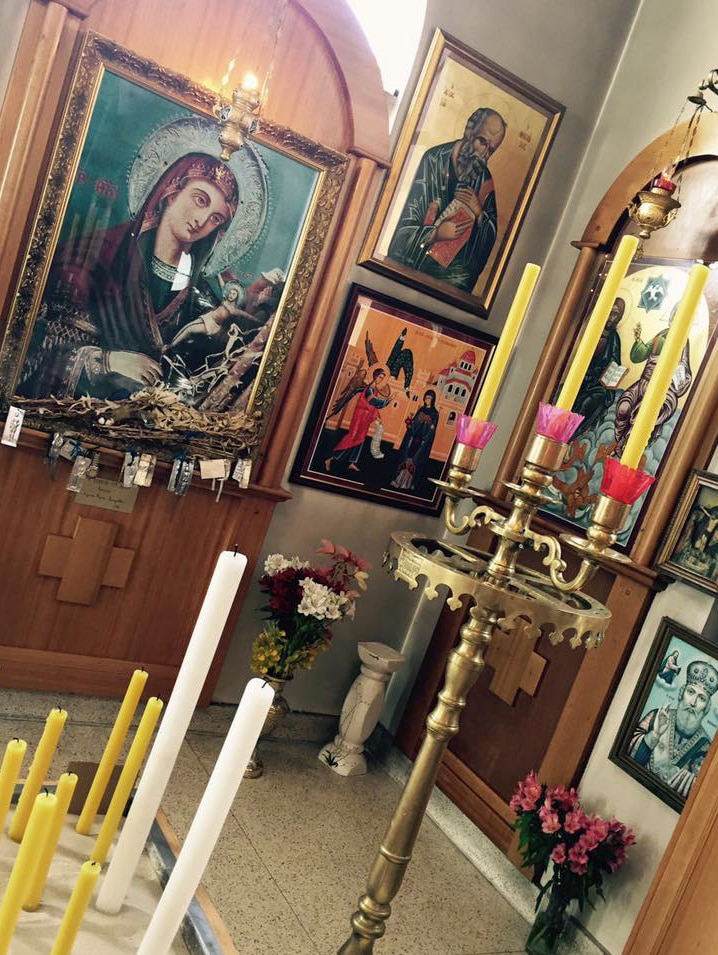 Religious icon paintings and large candle holders in an ornate church