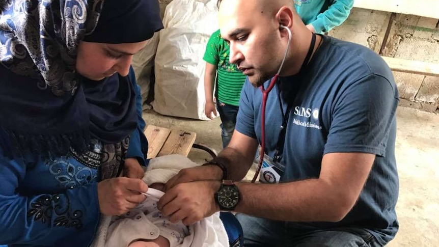 Dr Naveed Iqbal treats an infant on a medical mission with Syrian refugees in Lebanon.