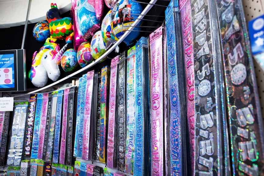 A display of colourful party items and balloons inside a store