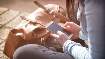 A person sitting down while using a mobile phone