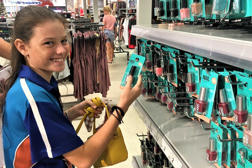 Madeline MacDonald choosing a girl's gift off a shop shelf to gift to the Christmas appeal