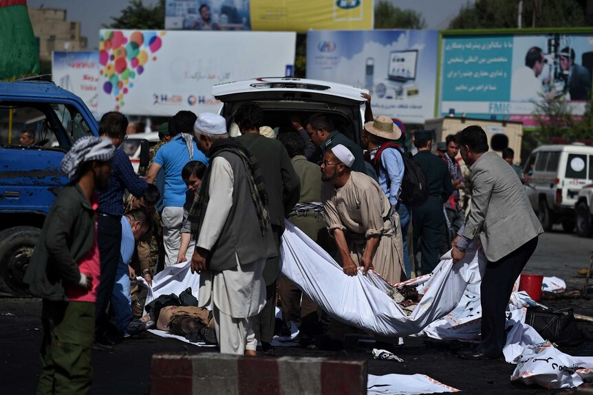 Afghan volunteers carry the bodies of victims at the scene.
