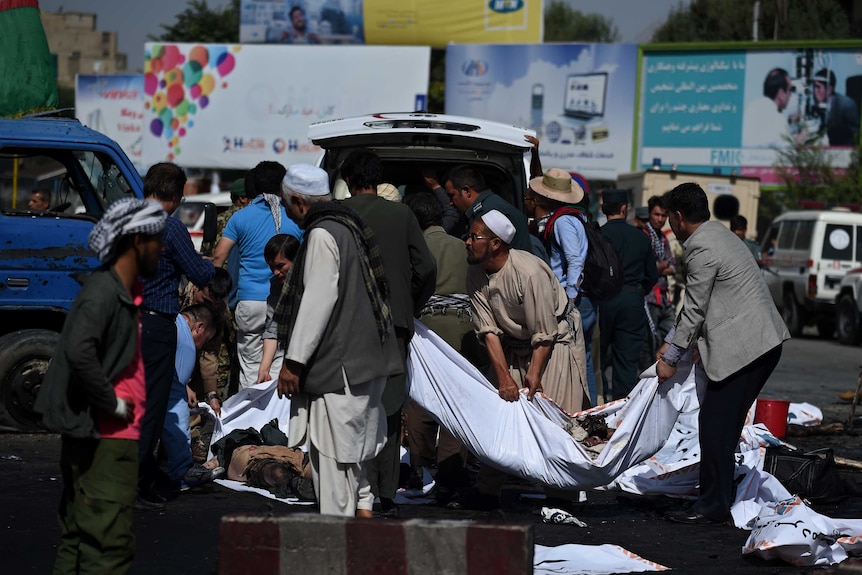 Afghan volunteers carry the bodies of victims at the scene.