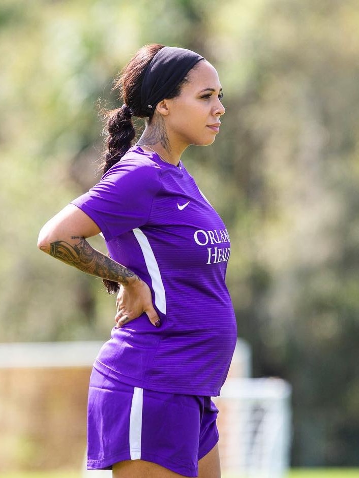 Sydney Leroux Dwyer stands with hands on hips with a pregnant belly visible through her shirt at Orlando Pride training.