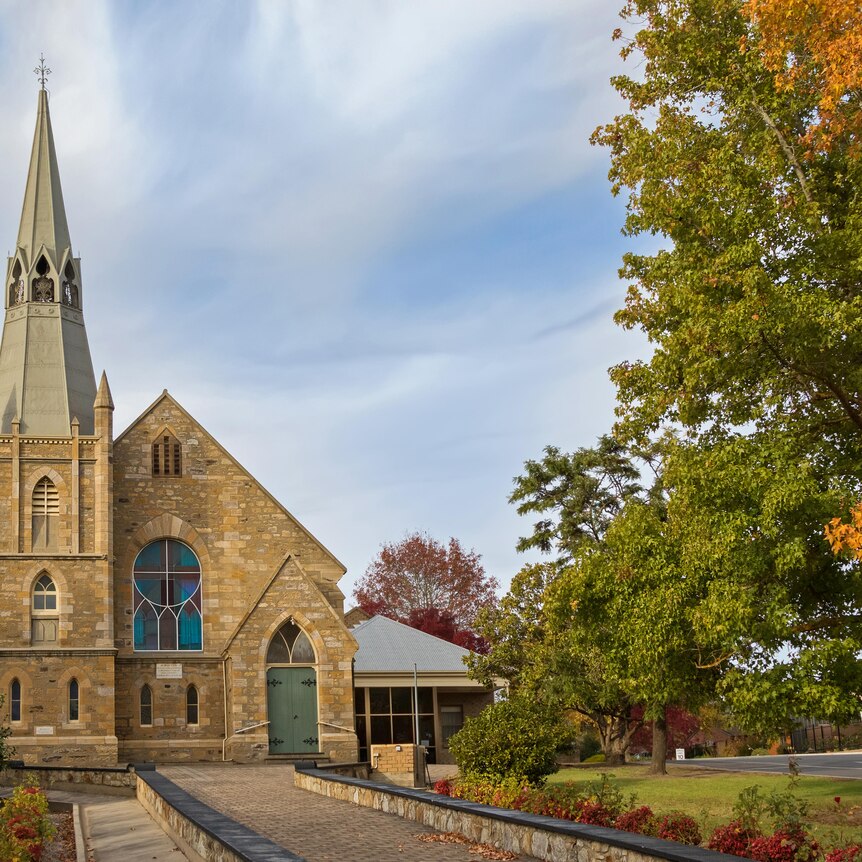 brick lutheran church with steeple amongst autumn leaves