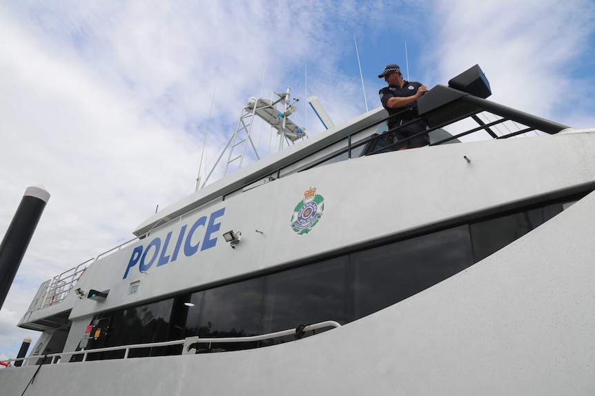 A police officer drives a large police boat backwards