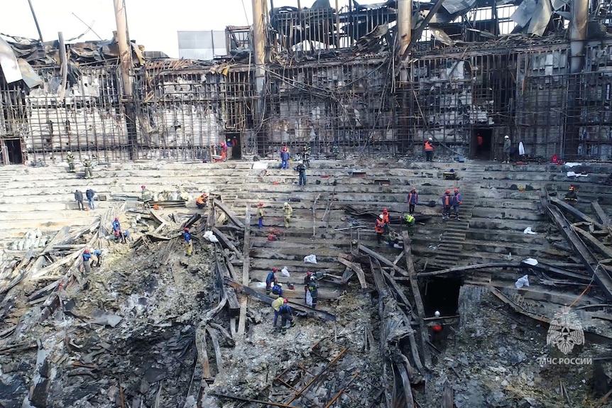 A large number of people cleaning the interior of a destroyed building, seen from a distance.