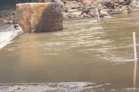 A big rock sits in the middle of a waterway.