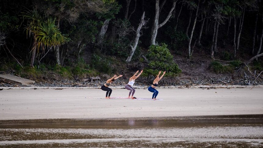 Women practice yoga on the beach at Byron Bay.