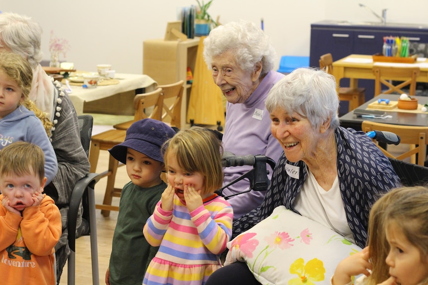 Two elderly lady with small children crowded around, all smiling