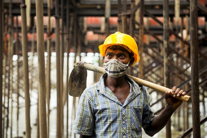 A young man in a hard hat and face mask