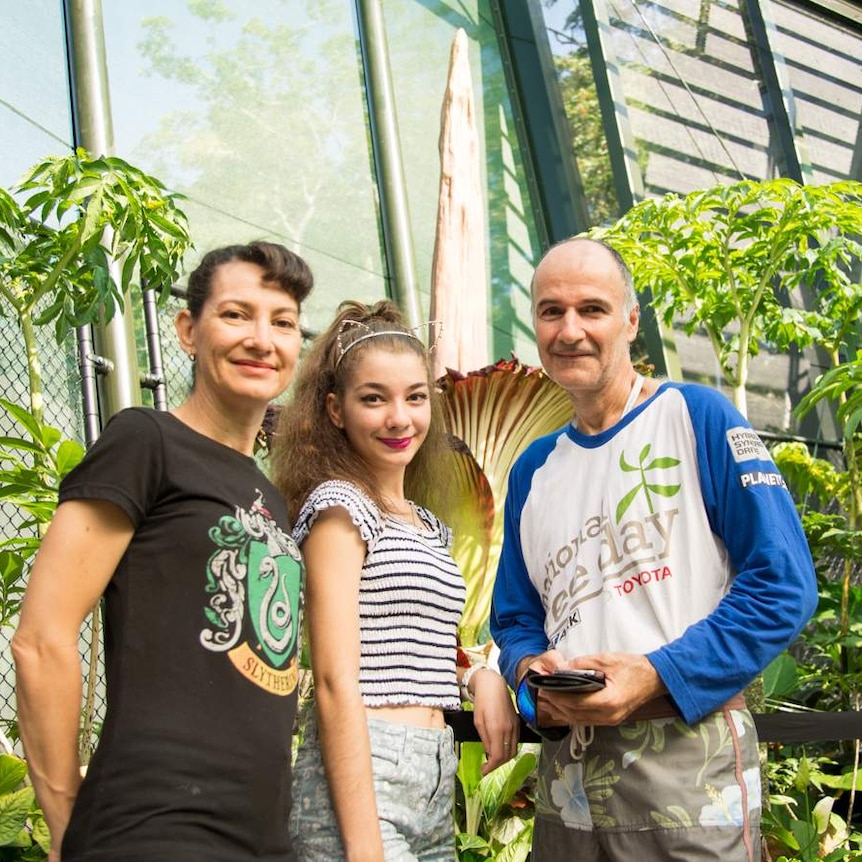 Lucy Torres, Nick Gounaris and Lucy Gounaris stand as a family in front of the Titan Arum bloom while holidaying in Cairns.