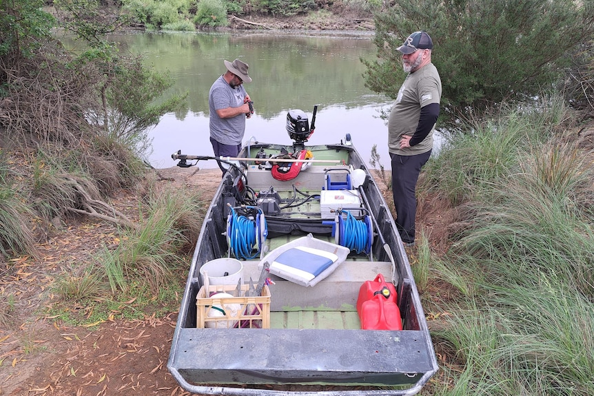 Two men and a boat next to a waterway