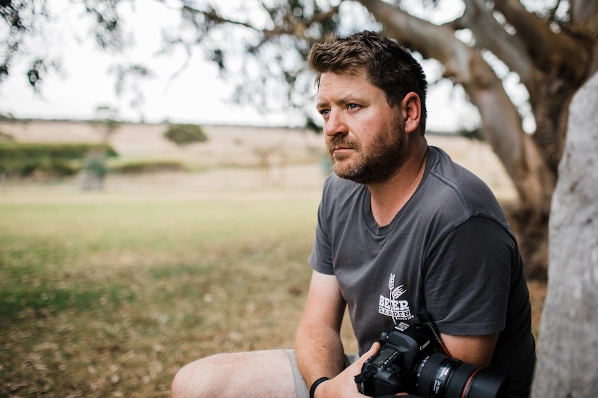 photograph of man in middle of photo, holding camera, pensive lighting