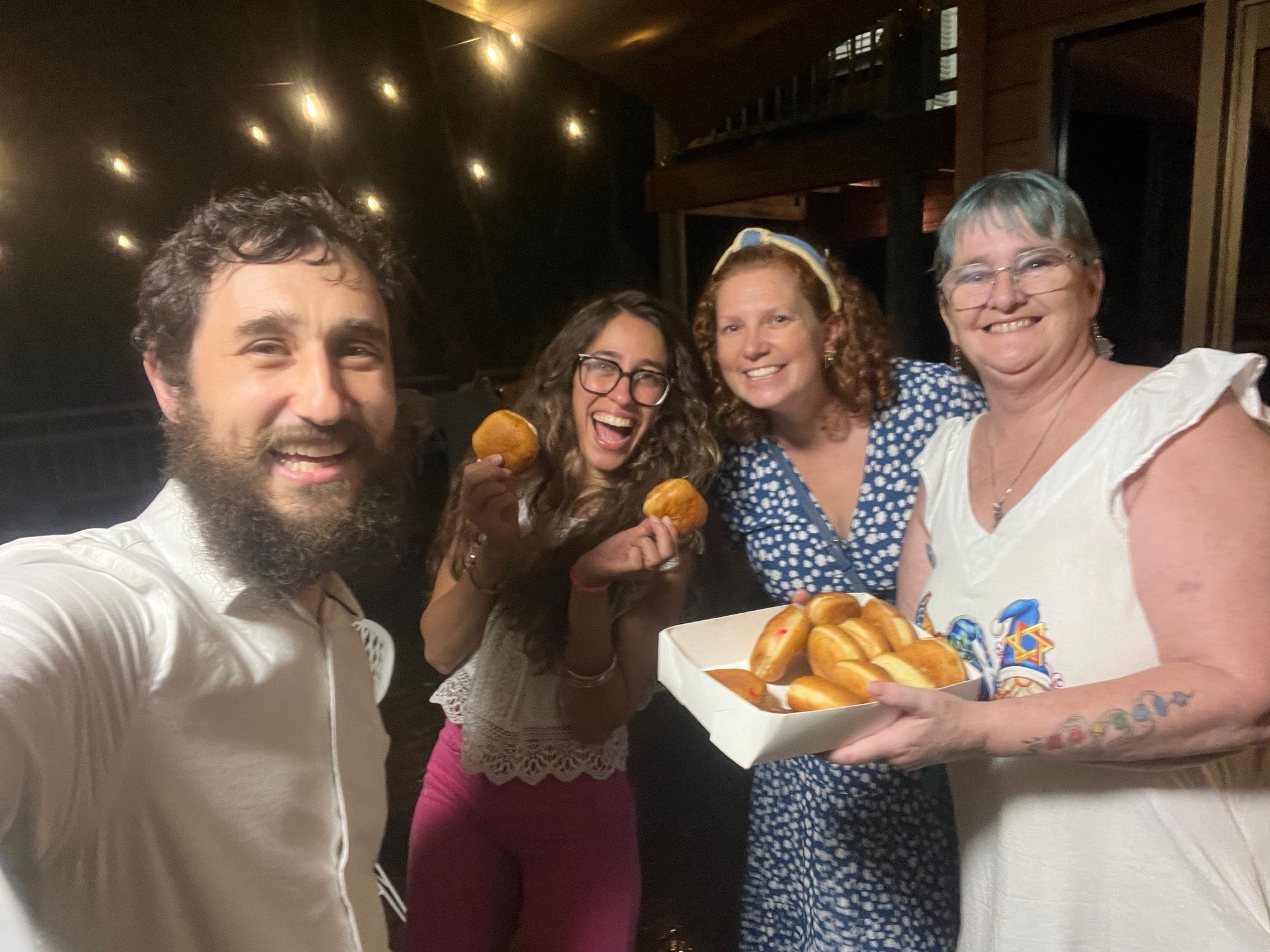 Cuatro personas sonríen y sostienen grandes donuts de mermelada.