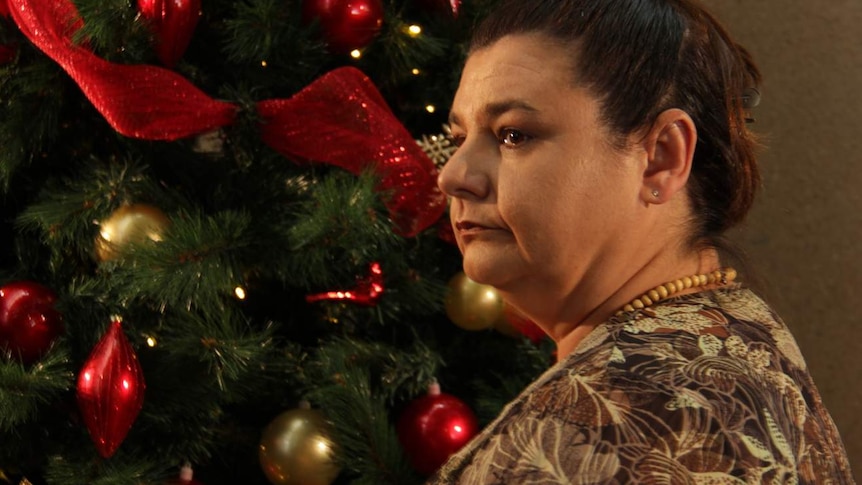 woman looking pensive in front of Christmas tree