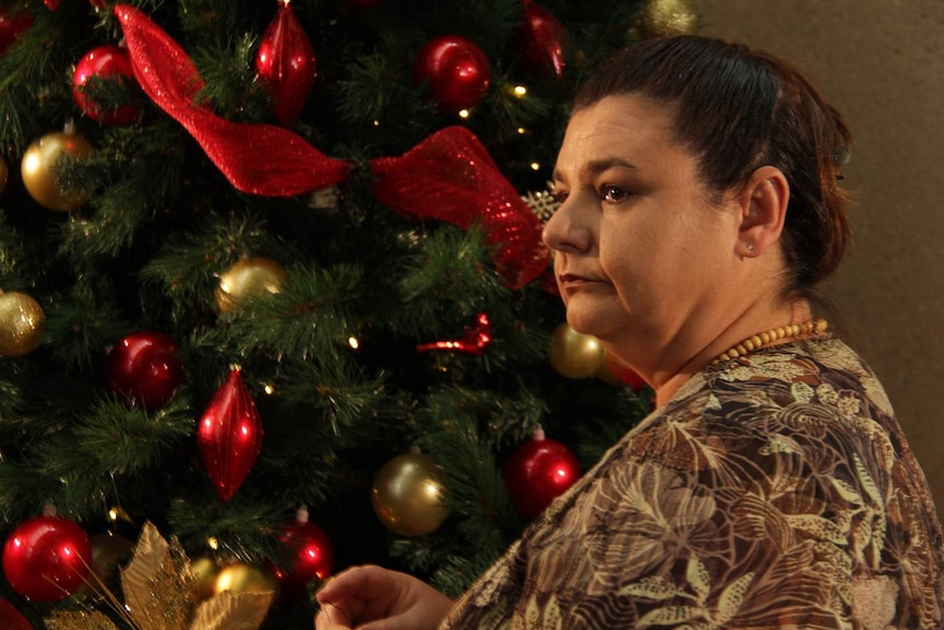 woman looking pensive in front of Christmas tree