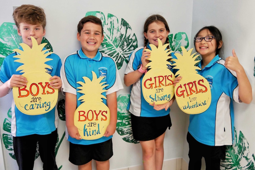 School students holding signs with positive gender messages.