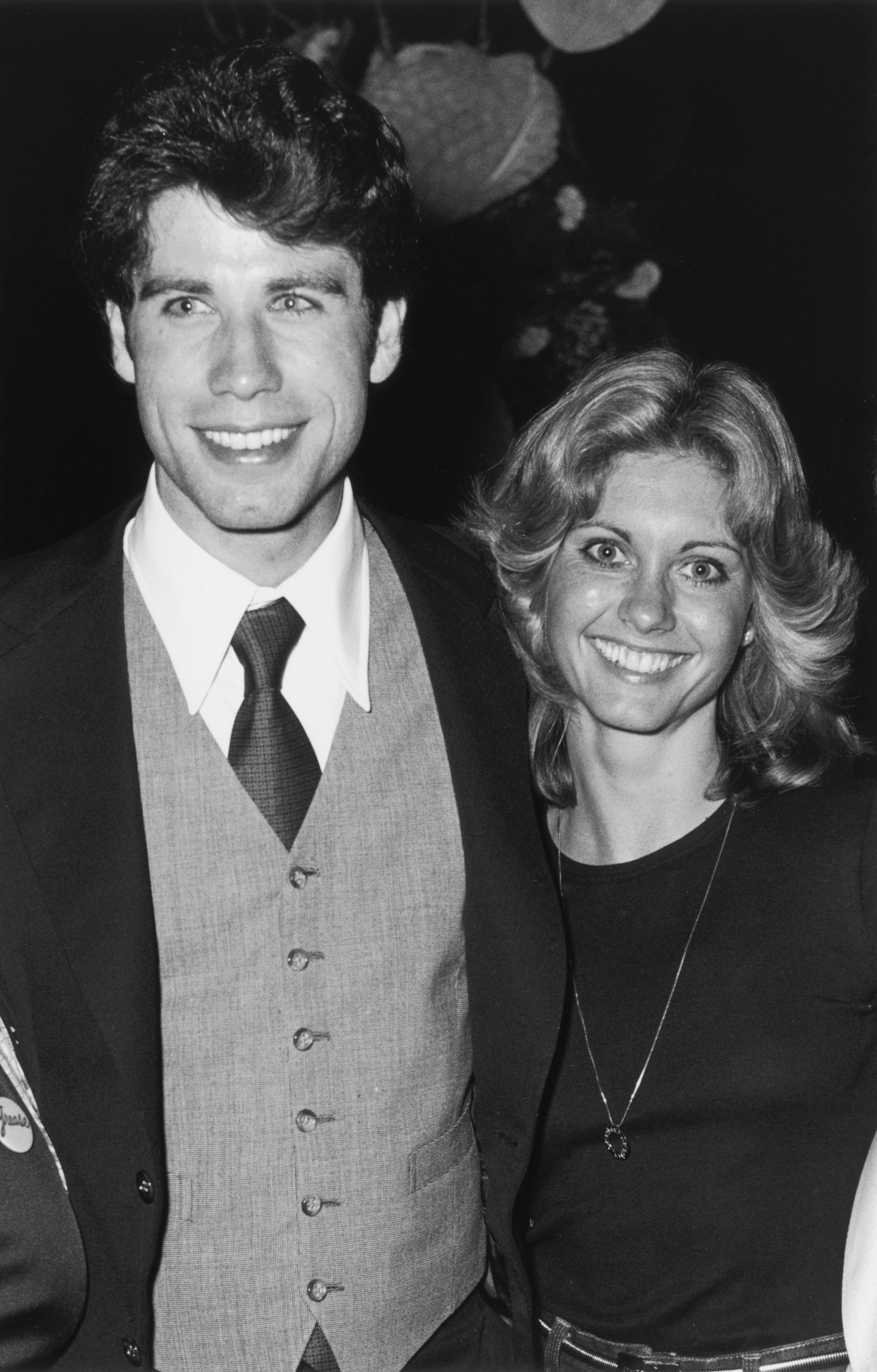 Black and white image of Olivia Newton John and John Travolta smiling at the camera.