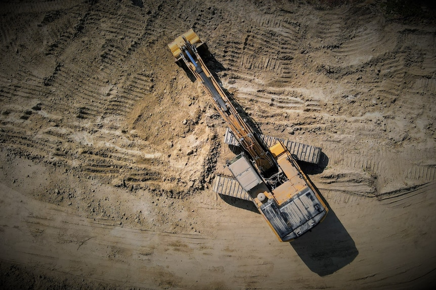 Aerial view of excavator in cleared area of land.