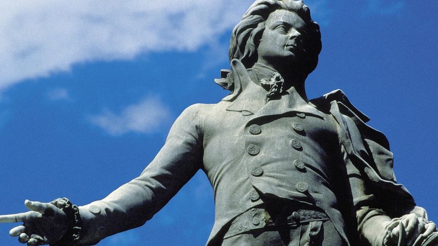 An imposing statue of the composer mozart, taken from a low angle with the sky in the background.