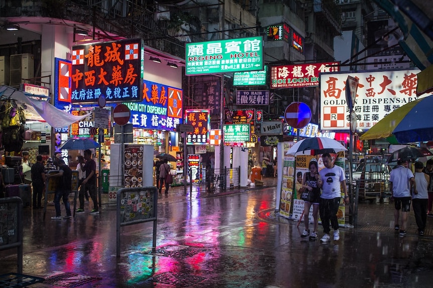 A street in Hong Kong showing lots of neon signs for hotels and restaurants.